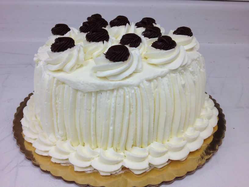 A cake with white frosting and chocolate berries on top