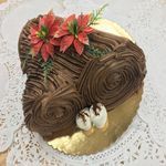 A chocolate cake with flowers on top is on a plate on a table.