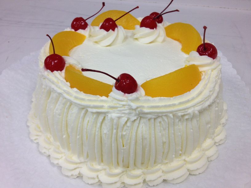 A white cake with cherries and peaches on top