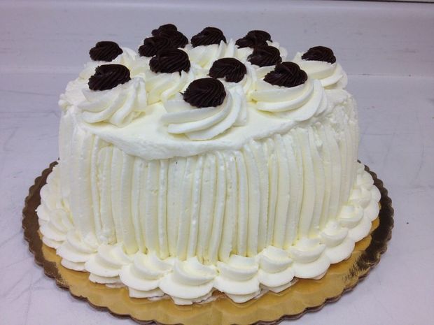 A cake with white frosting and chocolate berries on top