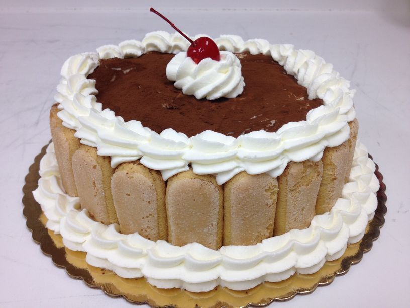 A cake with whipped cream and a cherry on top