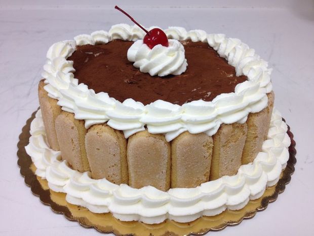 A cake with whipped cream and a cherry on top