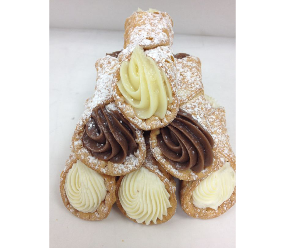 A stack of cannoli with chocolate and white frosting on a table.