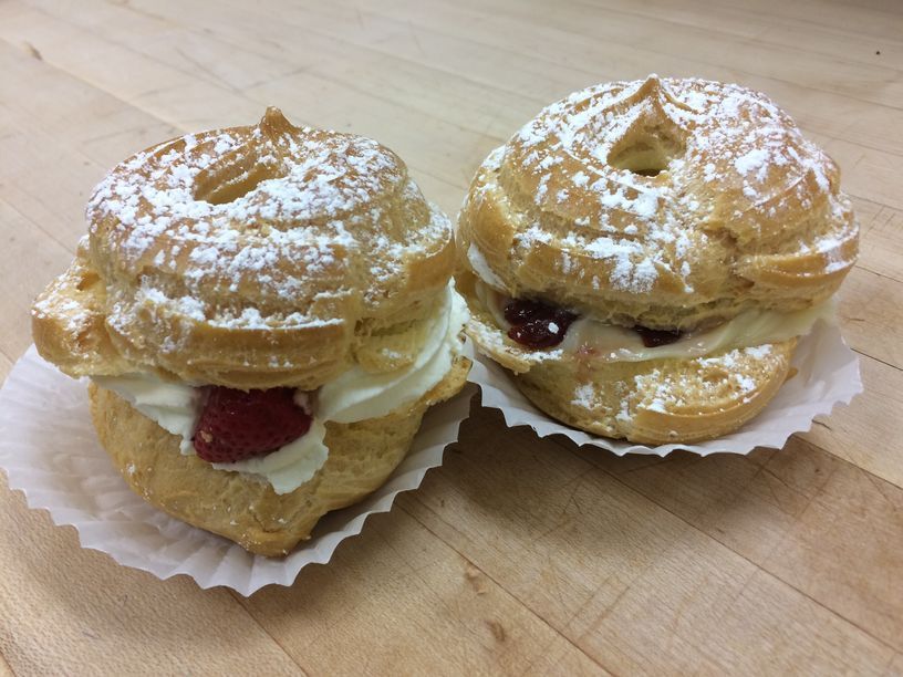 Two pastries with powdered sugar on them are sitting on a wooden table.