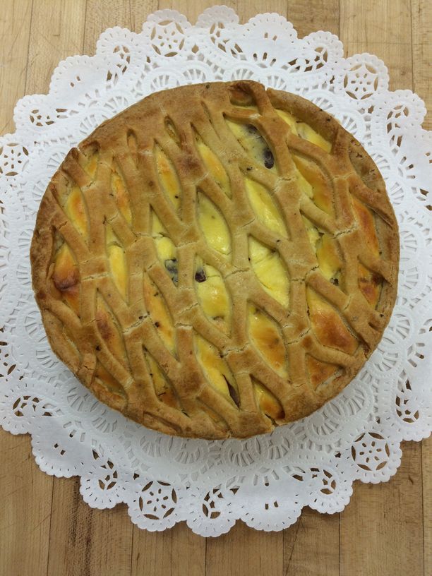 A pie is sitting on a white lace napkin on a wooden table.