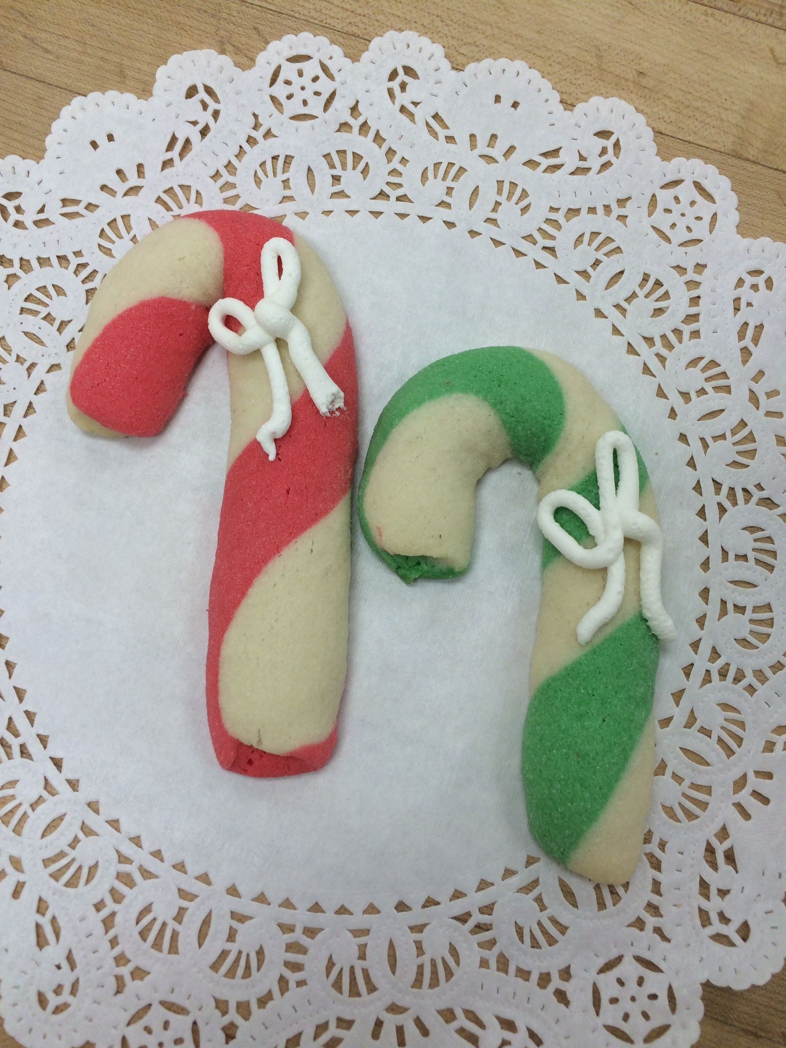 Two red and green candy canes on a white lace napkin