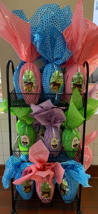 A display of easter eggs wrapped in tissue paper on a rack.