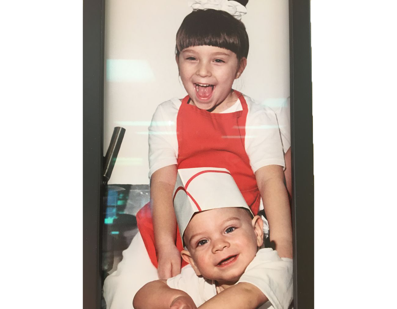 Two young boys wearing chef hats and aprons are posing for a picture.