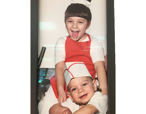 Two young boys wearing chef hats and aprons are posing for a picture.