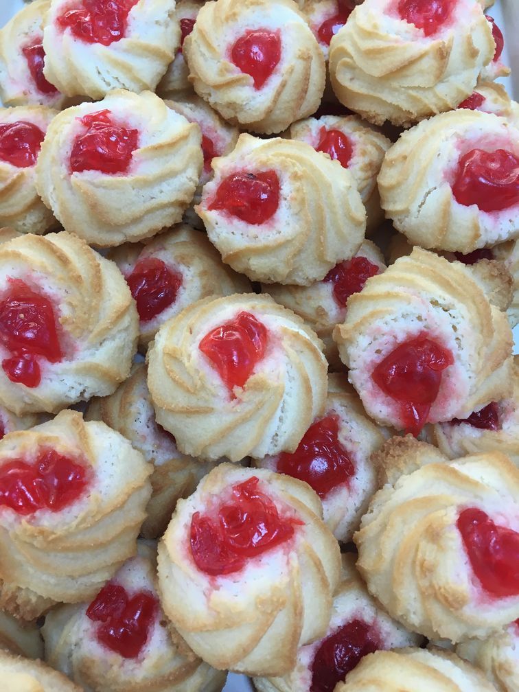 A pile of cookies with cherries on top of them