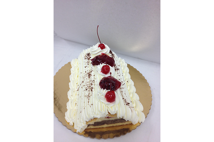 A slice of black forest cake with whipped cream and cherries on top.