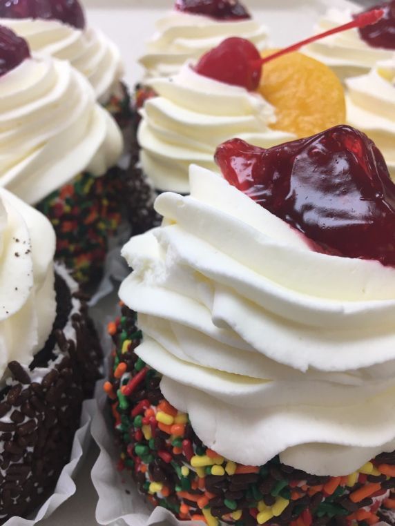 A cupcake with whipped cream and a cherry on top