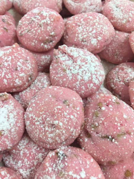 A pile of pink cookies with powdered sugar on top.