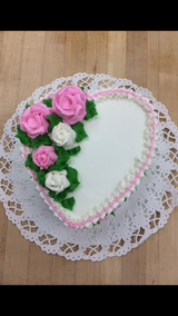 A heart shaped cake with pink and white roses on it