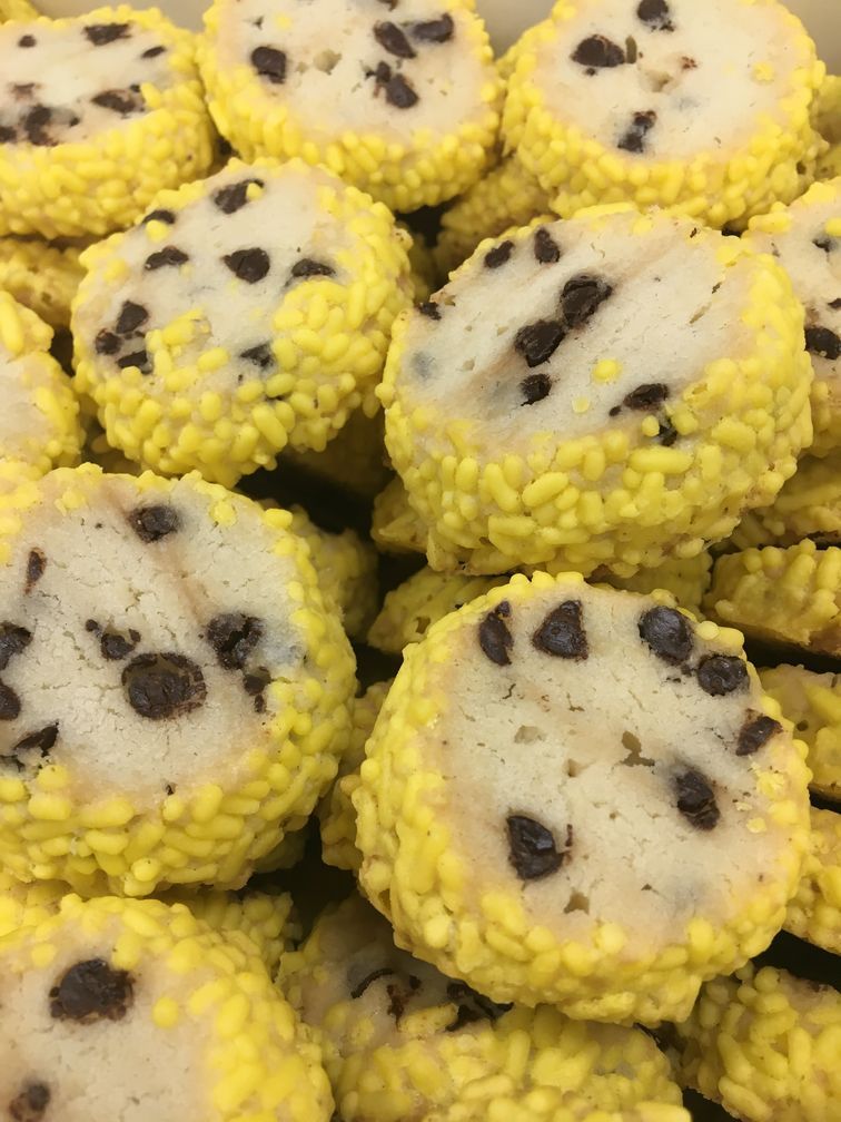 A close up of a pile of yellow cookies with chocolate chips on them.