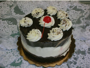 A black and white cake with whipped cream and a cherry on top