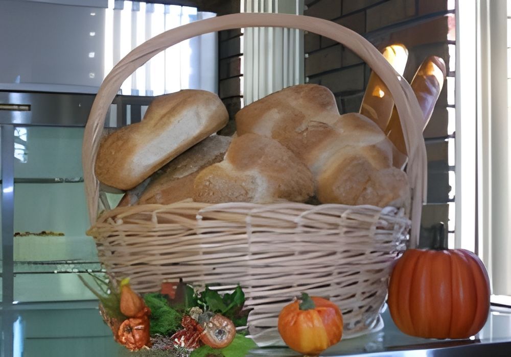 A wicker basket filled with bread and pumpkins on a table.