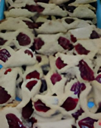 A bunch of cookies with berries on them are sitting on top of each other on a table.