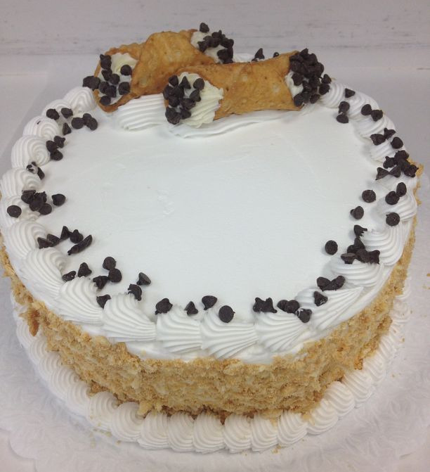 A cake with white frosting and chocolate chips on top