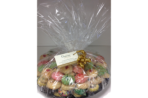A plastic bag filled with a variety of cookies is sitting on a table.
