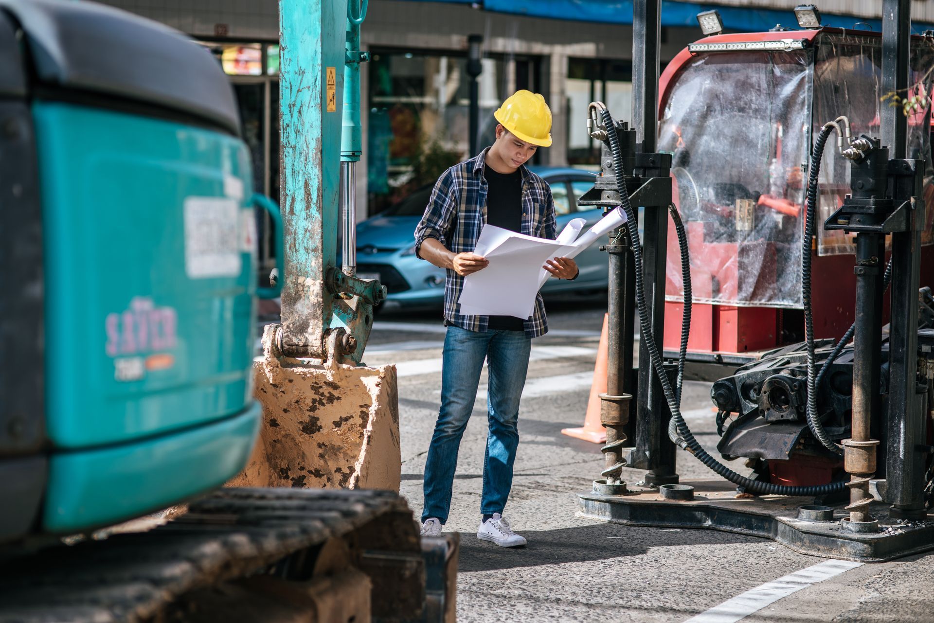 A man is standing on a construction site looking at a blueprint.
