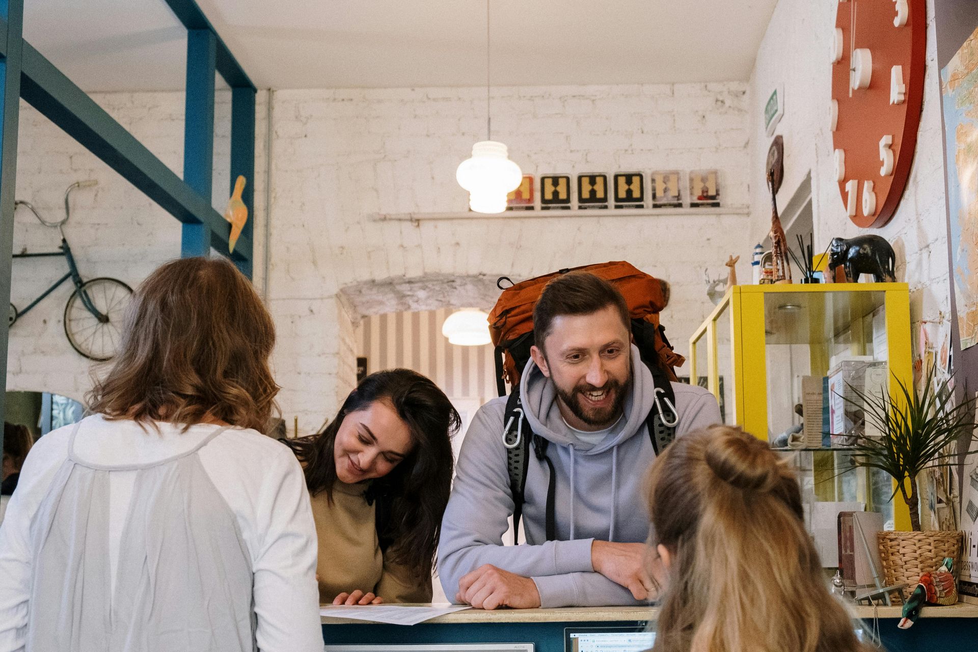 A man with a backpack is sitting at a counter with two women.
