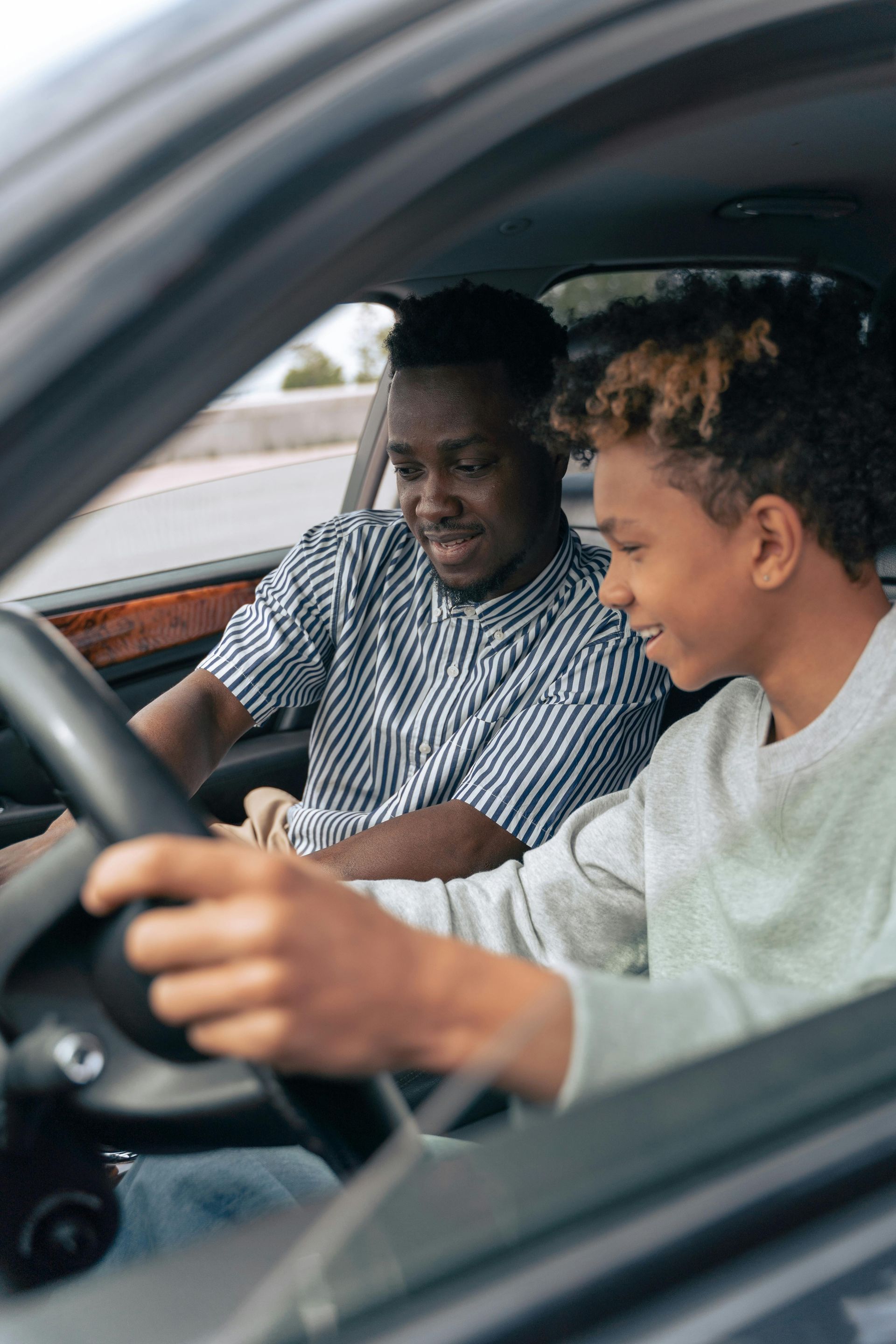 A man is teaching a boy how to drive a car.