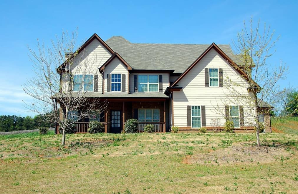 A large house is sitting on top of a grassy hill.