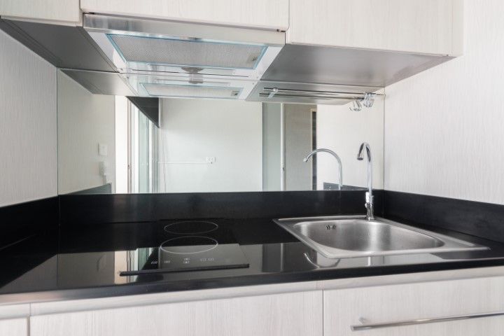 A clean and tidy kitchen counter, exhaust, stove, and sink.