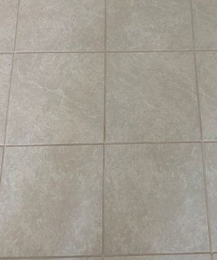 Beige square ceramic floor tiles with grout lines.