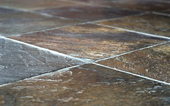 Close-up of brown and gray tiled flooring, with visible grout lines.