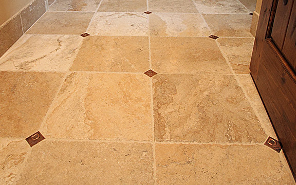 Beige and tan stone tile floor with copper square accents.