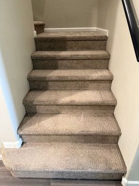 Carpeted staircase with beige steps and white trim, leading upwards.