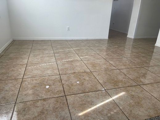 A light-filled room with brown tiled floor and white walls. Light reflects on the glossy tiles.