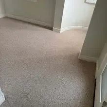 Beige carpeted room with light-colored walls and a doorway.
