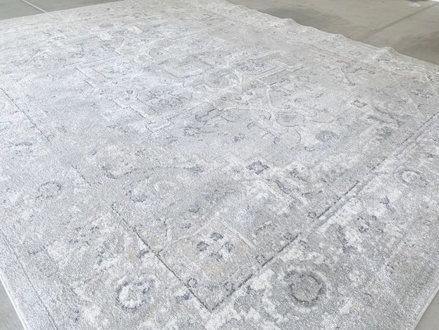 Light gray patterned rug, centered on a gray floor. Border and floral designs visible.