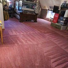 Pink carpeted room with furniture, stained and worn, showing foot traffic patterns.