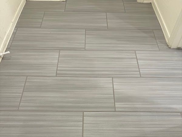 Gray rectangular wood-look tile flooring. Tiles are laid in a staggered pattern, in a room.
