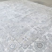 Light gray rug with a faded, detailed pattern.