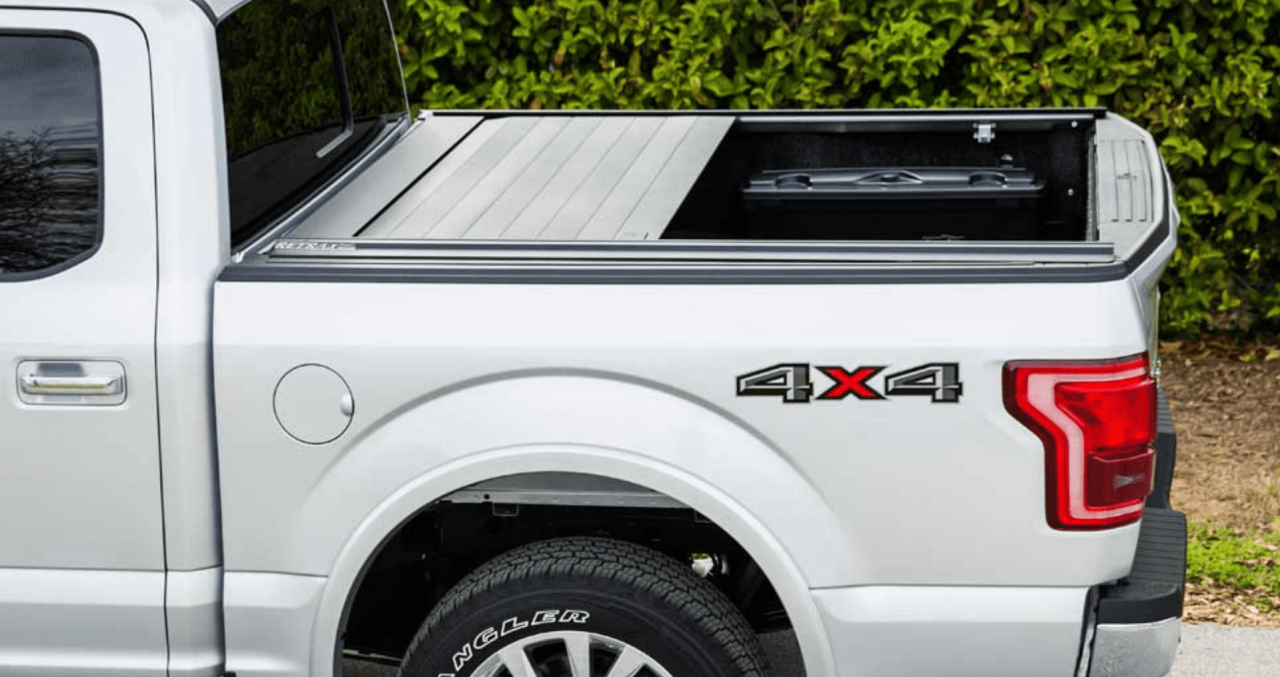 A white GMC Sierra pickup truck with black wheels parked in a parking lot next to a brick building.