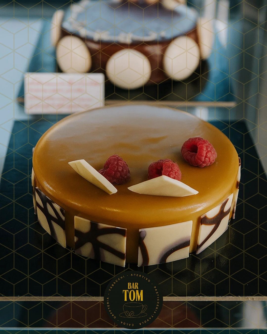 Torta con glassa al caramello, lamponi e dettagli di cioccolato bianco in mostra.