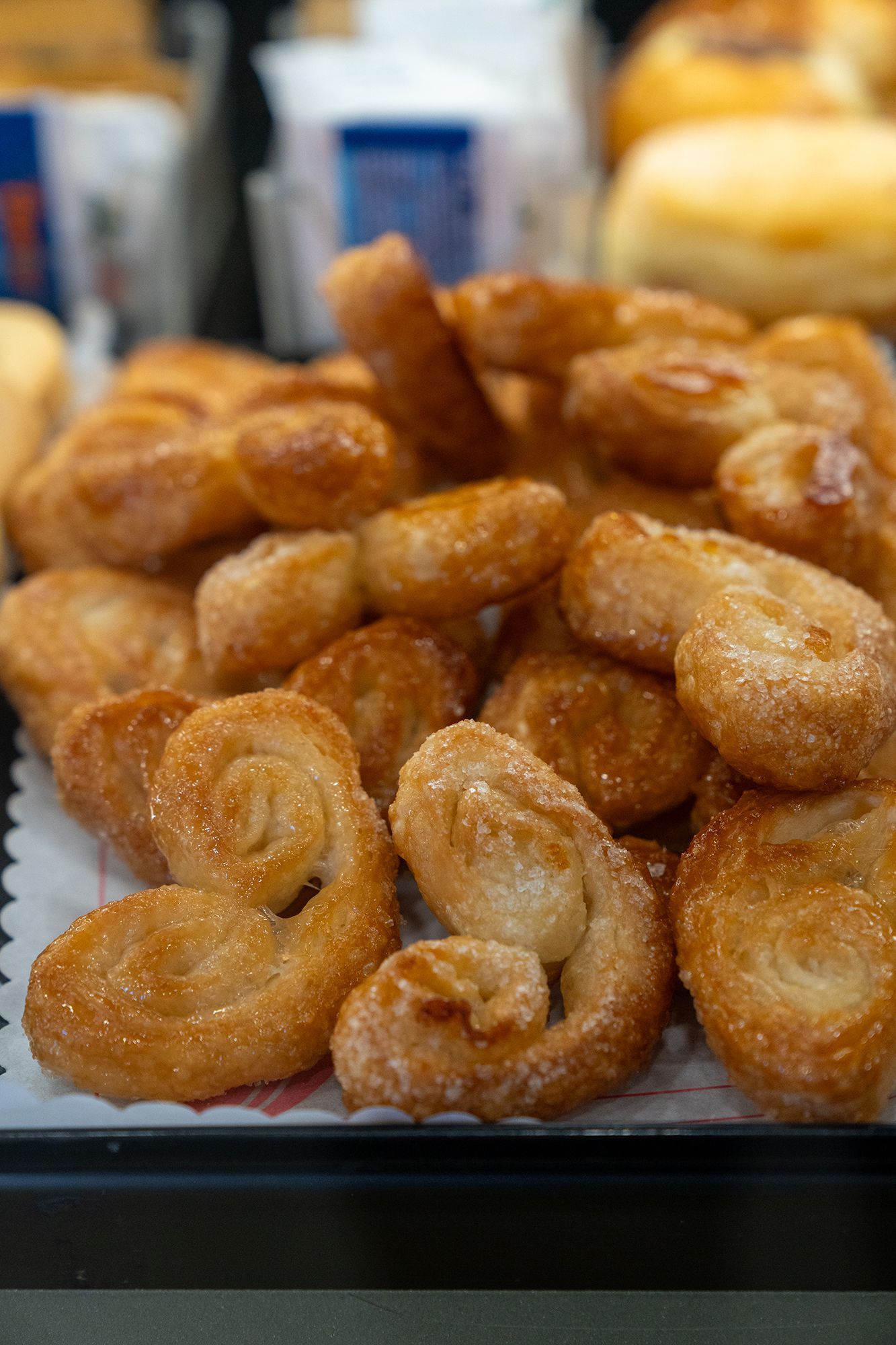 Una pila di pasticcini dorati ricoperti di zucchero, su un vassoio.