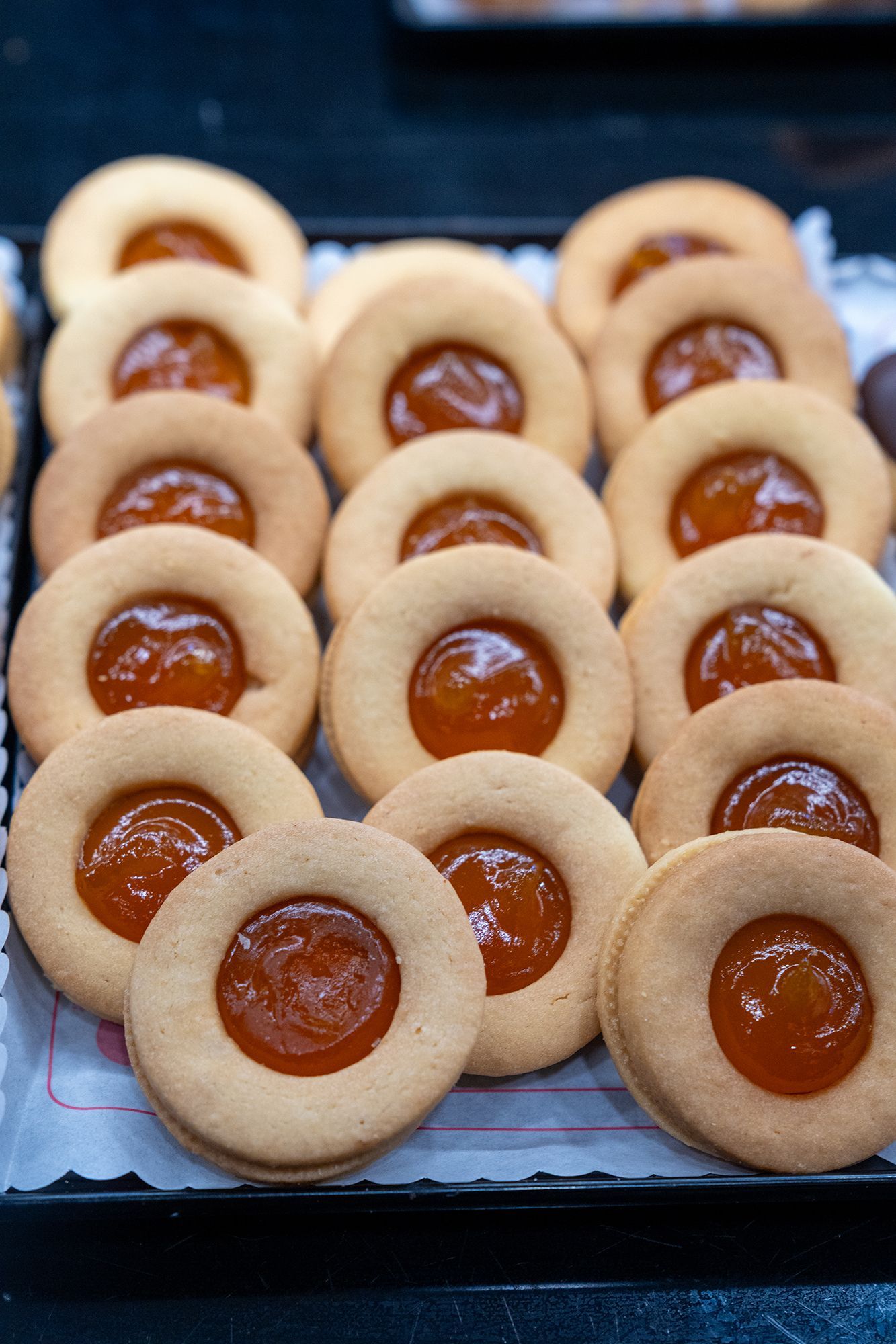 Biscotti con ripieno di marmellata di albicocche disposti su un vassoio.