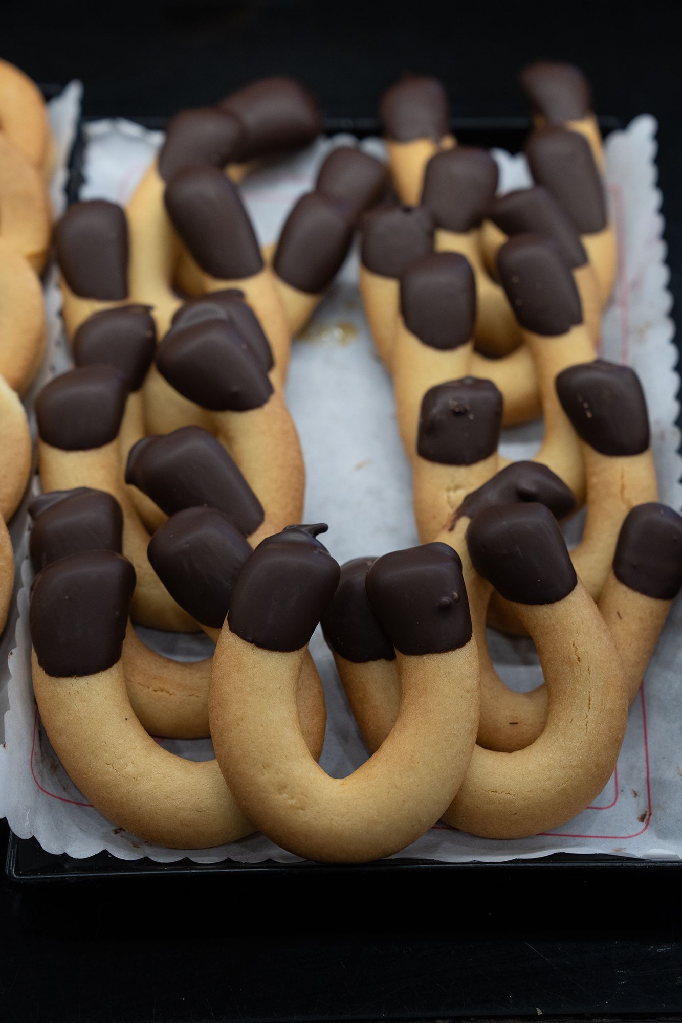 Biscotti a forma di ferro di cavallo, immersi nel cioccolato fondente, disposti su un vassoio.