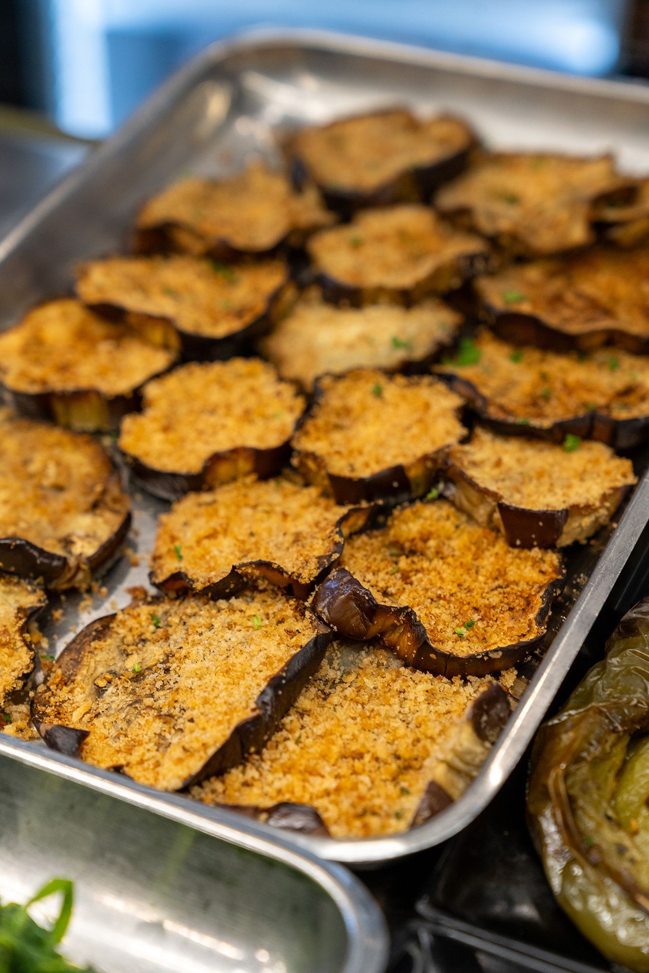 Melanzane a fette con pangrattato in una teglia di metallo.