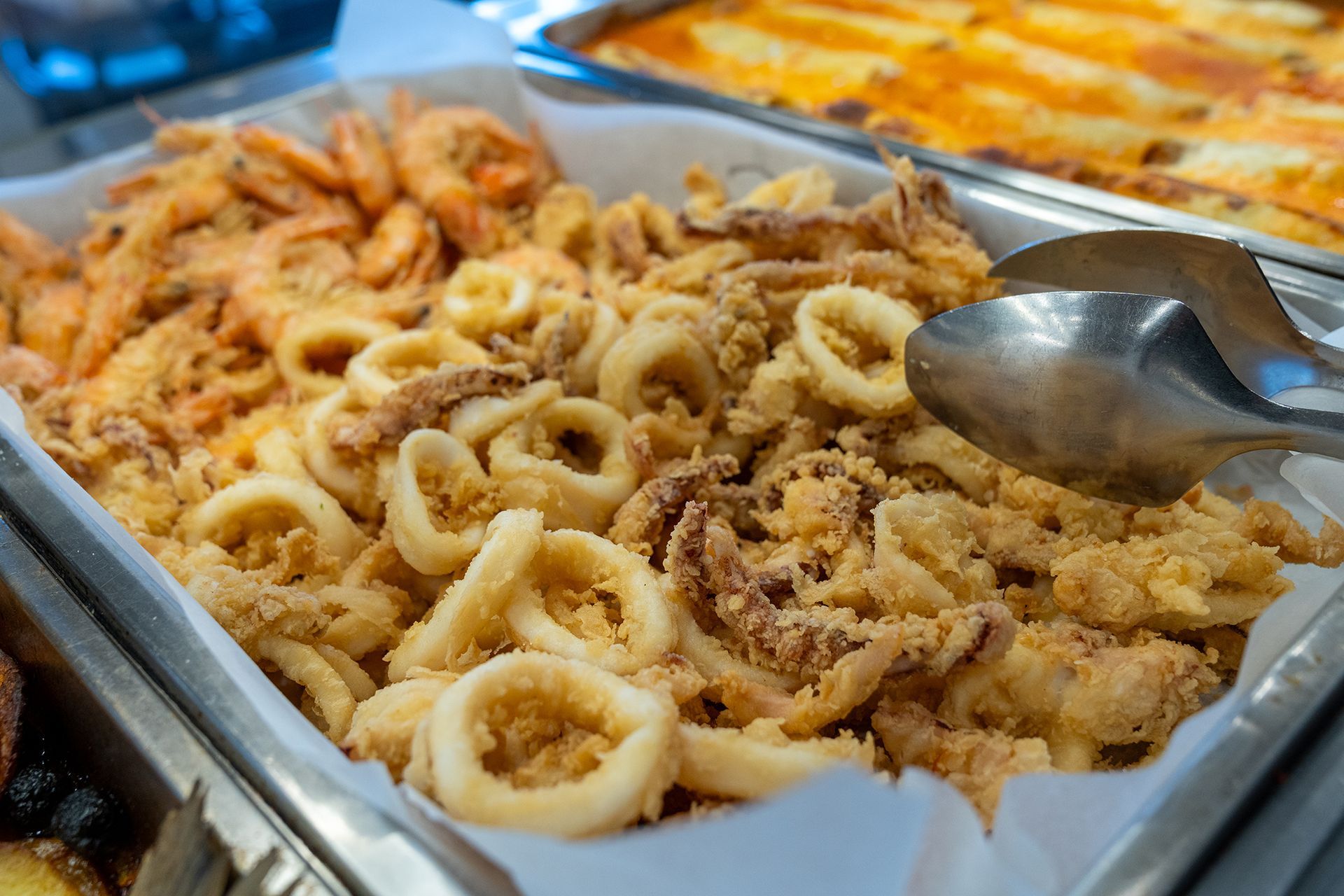 Frutti di mare fritti, tra cui gamberi e calamari, in un vassoio.