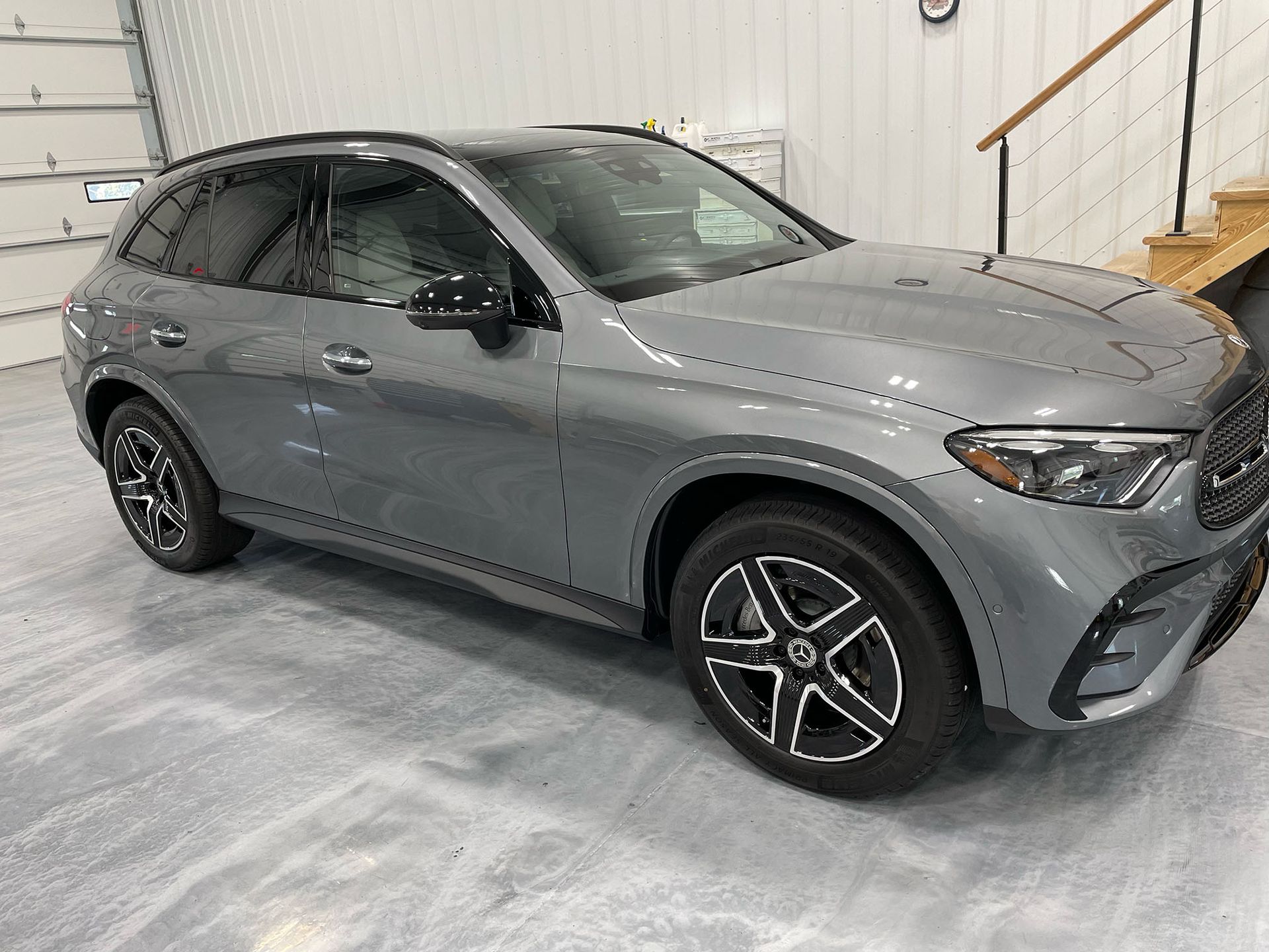 A gray suv is parked in a garage next to a staircase.