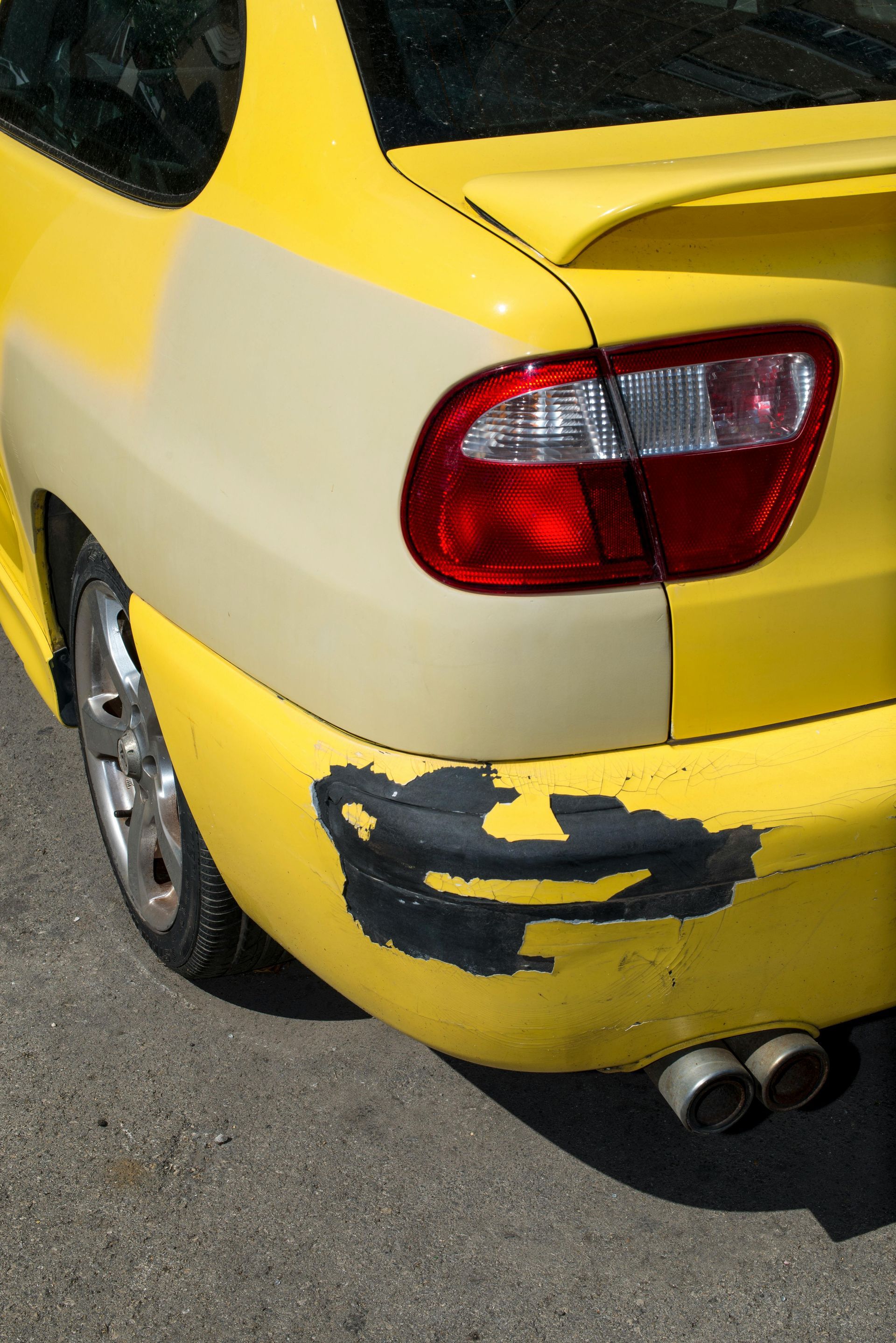 A yellow car with a bumper that has been damaged
