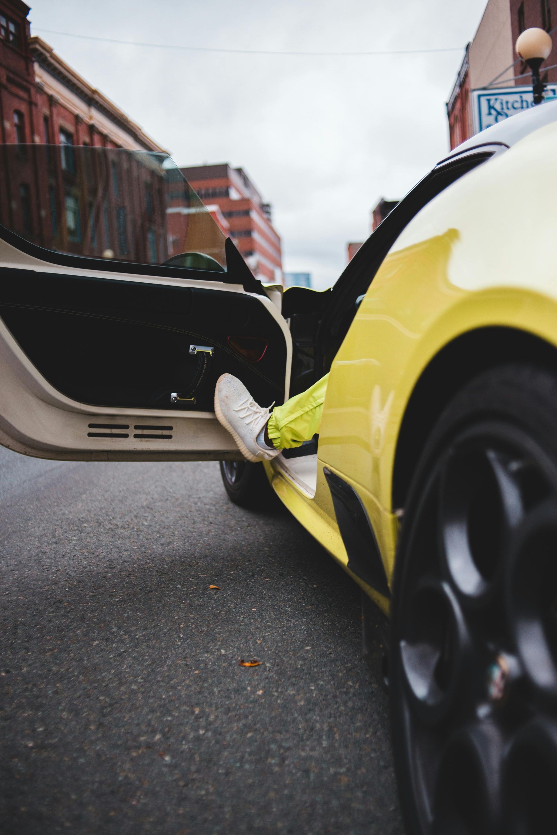 A person is sitting in a yellow sports car with the door open