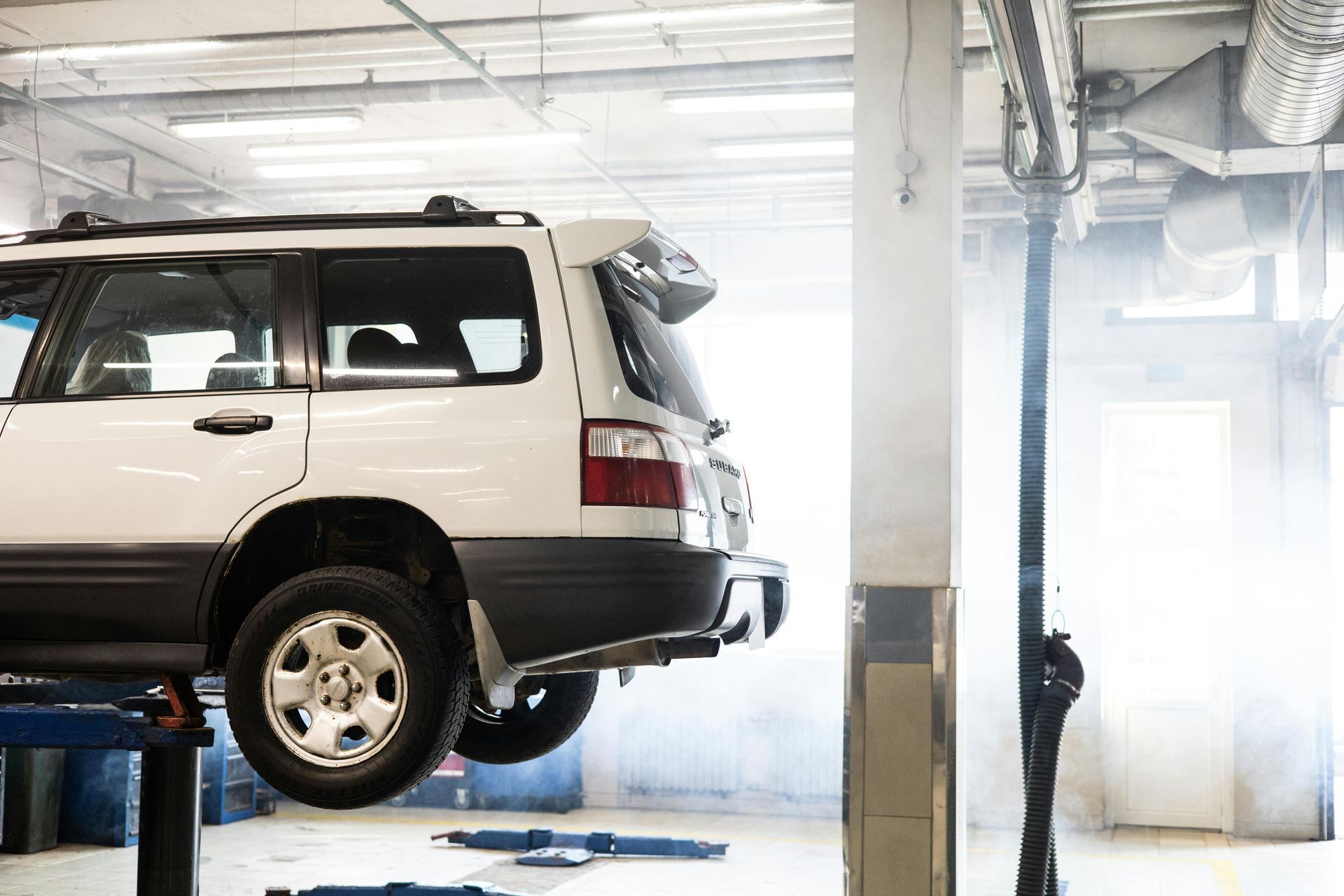 A white suv is parked on a lift in a garage.